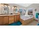 Bright bathroom boasting double sinks, bathtub, neutral tiles and a picture window at 8441 Urban Ct, Arvada, CO 80005