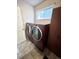 Functional laundry room with a modern washer and dryer set, cabinet, and a window for natural light at 8769 S Dudley St, Littleton, CO 80128