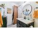 Bright bathroom with a round mirror, black vanity with a white countertop, wood flooring, and open door at 10150 E Virginia Ave # 19-303, Denver, CO 80247