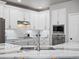 An open kitchen featuring stainless steel appliances, white cabinets, and a marble countertop island with a sink at 3043 W 109Th Pl, Westminster, CO 80031