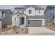 Two-story home featuring gray siding, stone accents, a two-car garage, and solar panels on the roof at 4903 Basalt Ridge Cir, Castle Rock, CO 80108