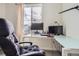 Bright home office featuring a glass desk, ergonomic chair, and a window with neighborhood views at 4903 Basalt Ridge Cir, Castle Rock, CO 80108