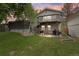 Spacious backyard featuring a deck with stairs leading down to a stone patio area and lush green grass at 12466 E Amherst Cir, Aurora, CO 80014