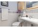Bathroom featuring white pedestal sink, toilet, decorative tiles, purple orchids and framed vintage print at 12466 E Amherst Cir, Aurora, CO 80014
