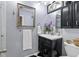 Bathroom with black vanity, floral accents, black and white tile flooring, and decorative mirror at 12466 E Amherst Cir, Aurora, CO 80014
