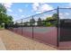 Well-maintained tennis court with a black fence and a gravel border, surrounded by mature trees at 12466 E Amherst Cir, Aurora, CO 80014