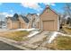 A street view showing a row of tan homes with attached garages and driveways under a bright, sunny sky at 13040 W 63Rd Pl # A, Arvada, CO 80004