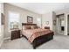 Spacious main bedroom featuring two windows, a wooden bed frame, and neutral carpeting at 6592 Club Villa Rd, Parker, CO 80134