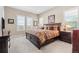 Spacious main bedroom featuring three windows, a wooden bed frame, and neutral carpeting at 6592 Club Villa Rd, Parker, CO 80134