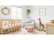 Bright Bedroom features a wooden crib, plush giraffe, and white armchair with natural light at 740 Meadowlark Dr, Erie, CO 80516