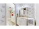 Bright bathroom with floral wallpaper, white vanity, and shower-tub combo providing a clean, classic design at 663 S Xenon Ct, Lakewood, CO 80228