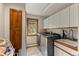 Well-lit laundry room with tile floors, washer, dryer, utility sink, and wood cabinets at 24768 Foothills N Dr, Golden, CO 80401