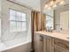 A bright bathroom featuring marble walls, a wooden vanity, and bathtub with shower at 4305 Red Rock Dr, Larkspur, CO 80118