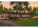 Exterior view of home featuring a large porch, well-maintained lawn, and a detached garage at sunset at 4305 Red Rock Dr, Larkspur, CO 80118