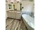 Bathroom with double vanities, granite countertops, wood floors, and soaking tub at 16063 E 106Th Ct, Commerce City, CO 80022