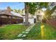 A large backyard with a grass lawn, stone pathway, and patio seating area at 1815 S Ogden St, Denver, CO 80210