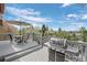Outdoor deck featuring a grill, table, umbrella, and seating area with a view of the trees and sky at 5531 S Telluride Ct, Centennial, CO 80015