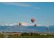 Scenic view of the community with hot air balloons, distant mountains, and green fields at 595 Twilight St, Erie, CO 80516
