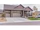 Beautiful stone exterior with a three-car garage and well-manicured lawn at 15804 Elizabeth Cir, Brighton, CO 80602