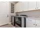 Functional laundry room with white cabinets, granite countertops, and stainless steel machines at 15804 Elizabeth Cir, Brighton, CO 80602