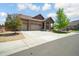 Charming home showcasing a three-car garage and inviting front yard, complemented by a lush tree and stone accents at 15804 Elizabeth E Cir, Thornton, CO 80602