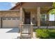 Inviting front porch featuring stone pillars and charming decor, adjacent to a three-car garage for convenience at 15804 Elizabeth E Cir, Thornton, CO 80602