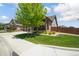 Well-maintained front lawn with mature trees and landscaped bushes, complete with a cozy porch and fenced yard at 15804 Elizabeth E Cir, Thornton, CO 80602