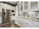 Modern kitchen with white cabinets, mosaic backsplash, granite countertops and stainless steel refrigerator at 15804 Elizabeth E Cir, Thornton, CO 80602
