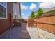Narrow side yard with gravel, stone pavers, a wood fence, and a gated access point at 15804 Elizabeth E Cir, Thornton, CO 80602