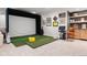 Basement golf simulation area with a large screen, putting green, and comfortable seating at 2475 S Adams St, Denver, CO 80210