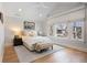 Sun-filled bedroom features neutral tones, a bench seat, a large window, and hardwood floors at 2475 S Adams St, Denver, CO 80210