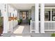 Inviting front porch featuring gray wood floors, white pillars and railings, and a black front door with glass panels at 2475 S Adams St, Denver, CO 80210