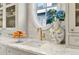 Kitchen with marble counters, white cabinetry, gold hardware, and a round window with blue hydrangeas at 2475 S Adams St, Denver, CO 80210