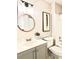 Bright bathroom with updated vanity, modern lighting, round mirror, and decorative wall art at 18064 E Ohio Ave # 202, Aurora, CO 80017