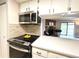 Kitchen with stainless appliances, black range, and a view into the living room with fireplace at 18064 E Ohio Ave # 202, Aurora, CO 80017