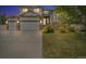Charming two-story home at twilight featuring a three-car garage, stone accents, lush lawn and mature trees at 5286 Rustic Ave, Firestone, CO 80504