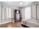 Cozy bedroom with hardwood floors, a dresser with TV, and two windows with natural light at 1295 S Downing St, Denver, CO 80210