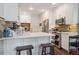 Bright kitchen features white cabinetry, stainless steel appliances, stone backsplash, and breakfast bar with stools at 1295 S Downing St, Denver, CO 80210