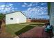 View of a fenced backyard with grassy areas, a brick patio, and a detached garage at 1391 Elmira St, Aurora, CO 80010
