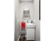 Small half-bathroom featuring modern sink and mirror with a sleek red accent towel and a trash can at 1391 Elmira St, Aurora, CO 80010