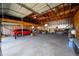 Interior view of a spacious garage with high ceilings, exposed beams, and ample storage and workbench space at 1391 Elmira St, Aurora, CO 80010