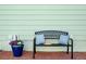Black metal patio bench with blue pillows and a hat; blue planter with purple flowers, against a light green wall at 1391 Elmira St, Aurora, CO 80010