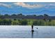 Scenic lake view with paddle boarder and mountain backdrop, ideal for outdoor enthusiasts at 7615 E Quincy Ave # 103, Denver, CO 80237