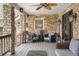 Cozy covered porch with stone walls, featuring stylish wicker seating, an overhead fan, and decorative lighting at 7836 S Fairfax Ct, Centennial, CO 80122