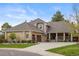 Beautiful home featuring a stone exterior, well-manicured lawn, mature trees, and a three car garage at 7836 S Fairfax Ct, Centennial, CO 80122