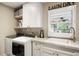 Bright laundry room features white cabinetry, marble countertops, stainless steel faucet and modern washer and dryer at 7836 S Fairfax Ct, Centennial, CO 80122