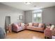 Bright sitting room features hardwood floors and is furnished with pink sofas and an accent chair at 7836 S Fairfax Ct, Centennial, CO 80122