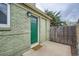 Exterior side entrance with a green door, light fixture, and adjacent wooden fence at 3640 Elm St, Denver, CO 80207