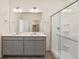 Bright bathroom features a double sink vanity, a glass enclosed shower, and neutral tile flooring at 845 Leeward St, Lochbuie, CO 80603