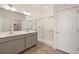 Bright bathroom features a double sink vanity, a glass enclosed shower, and neutral tile flooring at 845 Leeward St, Lochbuie, CO 80603